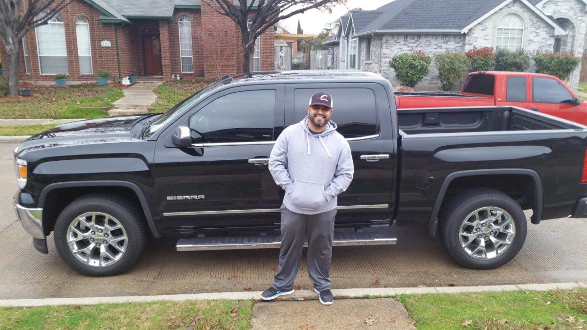 Male customer in front of new black truck lease