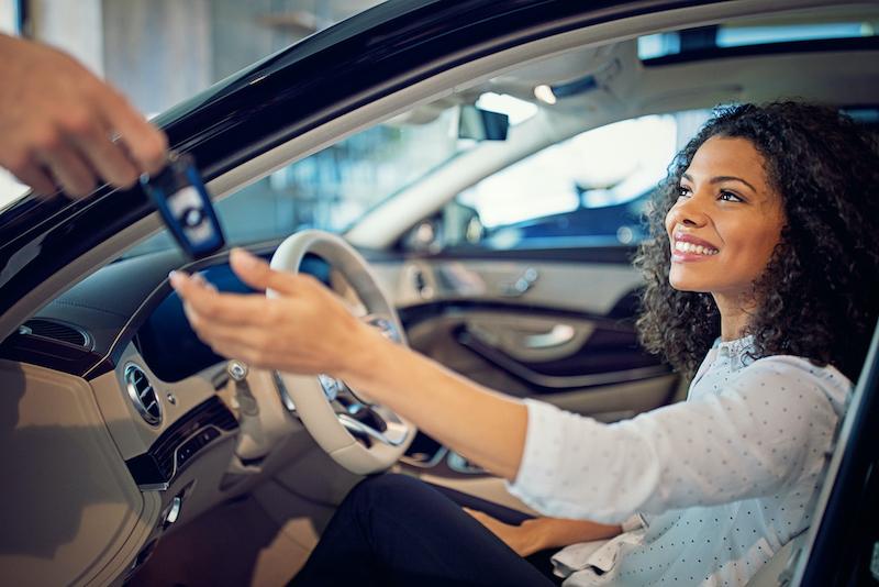 Car dealer giving keys to a woman for a new car lease