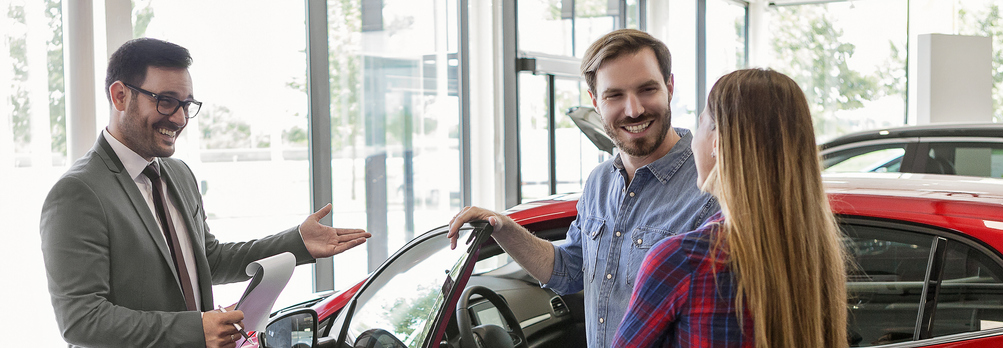 Couple looking into EZ leasing a pre-owned red car